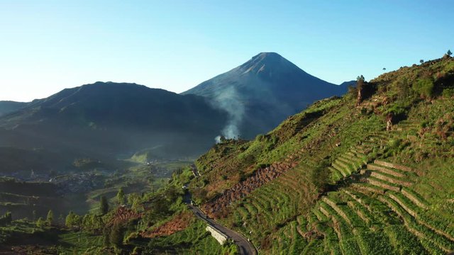 Beautiful aerial view of plantation land in Dieng Plateau with Mount Sundoro background at Wonosobo, Cental Java, Indonesia. Shot in 4k resolution from a drone flying forwards