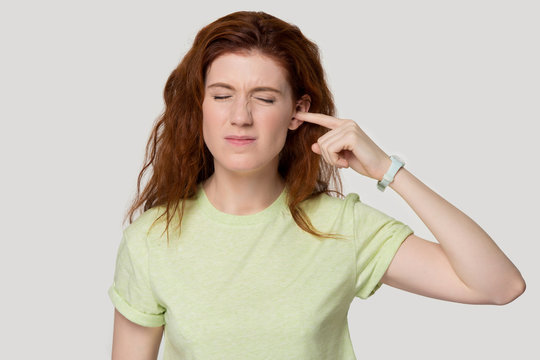 Studio headshot young woman suffering from ear pain or noise