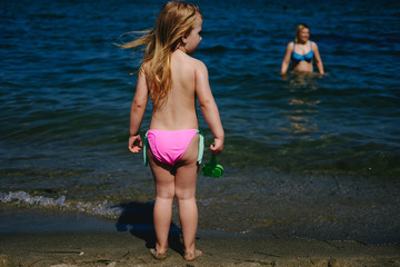 Little Girl on a Beach with Her Mother in the Water