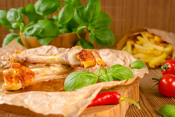 food leftovers from grilled chicken and chilli with tomato, fries and basil on wooden background