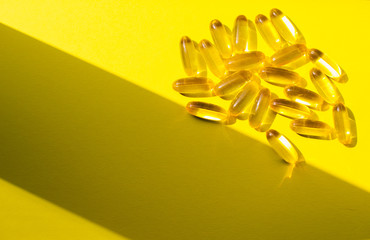 Fish oil capsules on a yellow background. Omega 3, omega 6, omega 9. Top view, copy space.