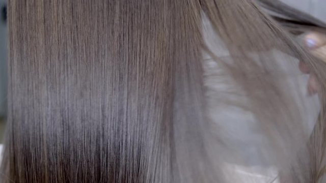 hairdresser makes hair lamination in a beauty salon for a girl with brunette hair