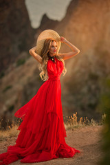 Young beautiful woman in red dress looking to mountains sea