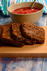 The soup in the plate on the table. Sliced grain bread. Lunch in rustic style.