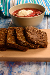 The soup in the plate on the table. Sliced grain bread. Lunch in rustic style.