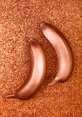 Bronze colour food, copper banana on glitter or shimmer background. Trendy tropical flat lay. Creative concept