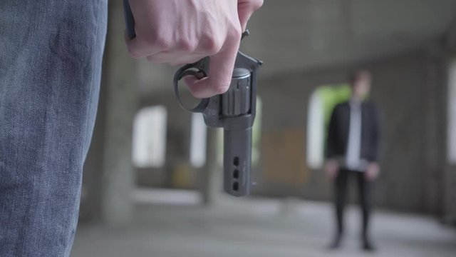 Person with a gun going to shoot and kill a man standing in front of her in abandoned building. Close up