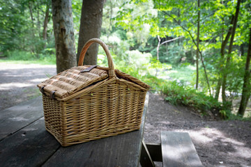 Wicker picnic basket on picnic table, at recreational campsite or picnic site.
