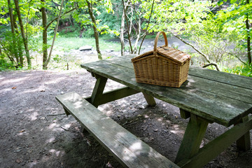 Wicker picnic basket on picnic table, at recreational campsite or picnic site.