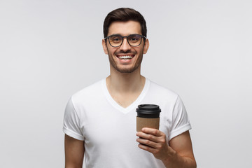 Handsome laughing man holding takeaway coffee cup, wearing white t-shirt and glasses, isolated on...