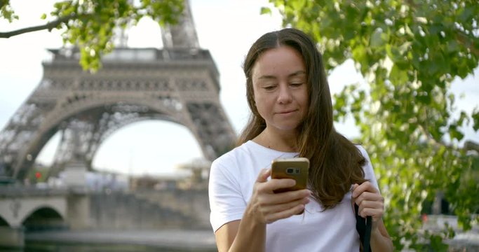 woman tourist uses phone against Eiffel Tower slow motion