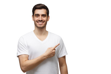 Young man in casueal t-shirt pointing right with his finger isolated on white background