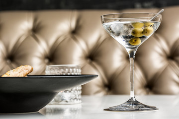 Beautiful glass of martini with olives accompanied by a gourmet dish.