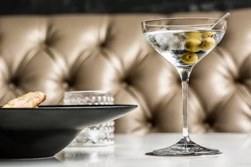 Beautiful glass of martini with olives accompanied by a gourmet dish. © silvapinto