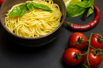 Italian food ingredients: pasta, olives, tomato paste, tomatoes, lime, olive oil, Basil on a black background. Healthy food concept, plant background, natural eco-products, organic food, vegetarian