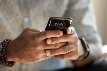 African man holding cellphone using applications, close up view
