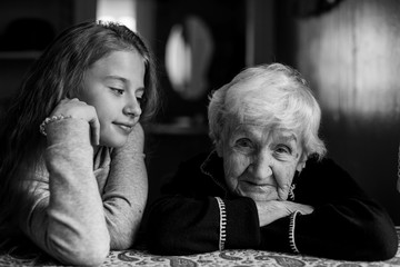 An elderly grandmother with her little granddaughter. Portrait black and white.