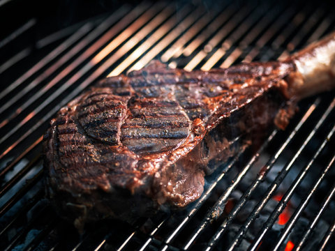 Angus beef tomahawk steak being grilled on a BBQ