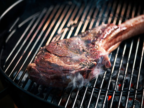 Angus beef tomahawk steak being grilled on a BBQ