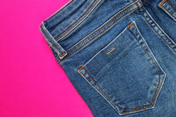 Blue jeans - back pockets close-up on a bright pink background. The concept of fashion, style,...