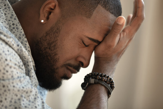 Upset stressed young african american man coping with strong headache