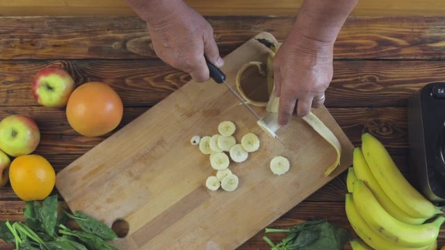 Elderly man is cutting banana for healthy and wellness cocktail