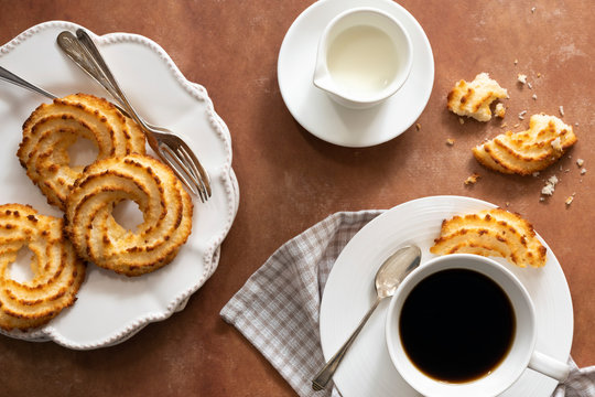 Cup of coffee served with coconut macaroons on a plate.