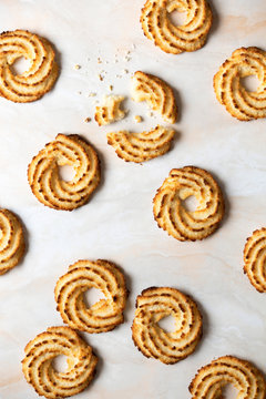 Scattered coconut cookies with one broken into pieces.