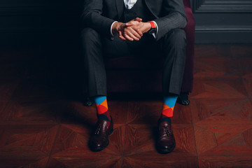 Portrait of a businessman in strict gray suit and colorful multi colored socks. Business and...