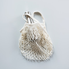 Fototapeta premium Empty shopping mesh bag with metal bottle on grey. Zero waste concept.