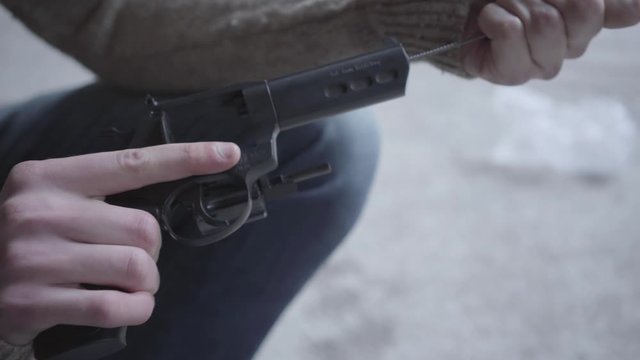 Hands of young man dismantle and clean the gun close-up. The guy preparing to kill human or commit suicide