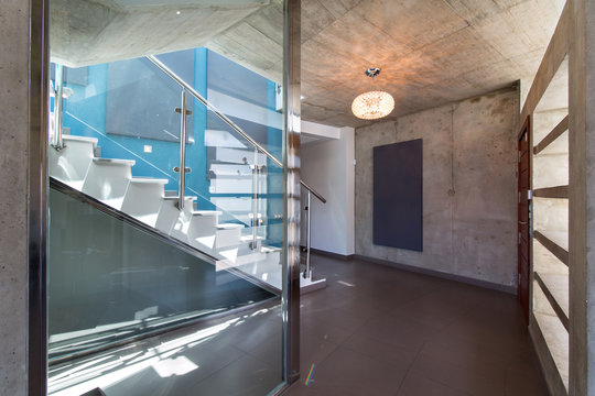 stairs in interior of modern concrete house, with blue wall and luminaire.