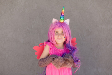 A cute girl is dressed up like a unicorn with a colorful wig, headband, ears, hooves and wings.  © falonkoontz