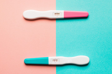 Positive pink and blue plastic pregnancy test on pink background