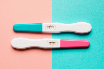 Positive pink and blue plastic pregnancy test on pink background