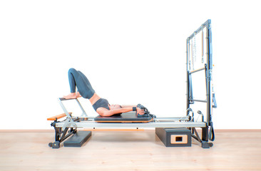 Fototapeta premium Young girl exercising on pilates reformers beds