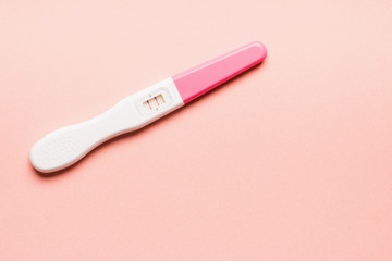 Positive pink plastic pregnancy test on pink background.