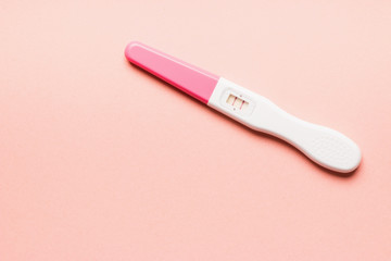 Positive pink plastic pregnancy test on pink background.