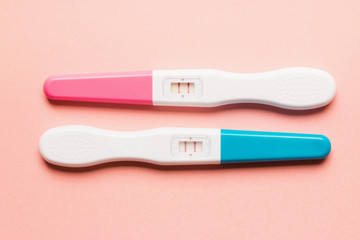 Positive pink and blue plastic pregnancy test on pink background