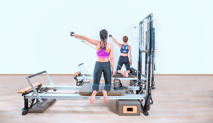 Fototapeta premium Young women exercising on pilates reformers beds
