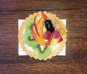 Delicious pastry cake with fresh fruit on table