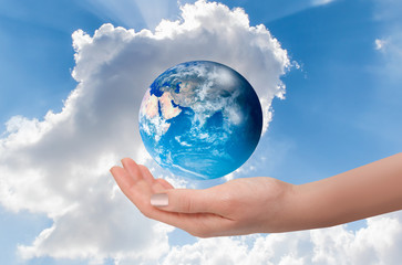 Woman holding globe on her hand with bright blue sky "Elements of this image furnished by NASA"