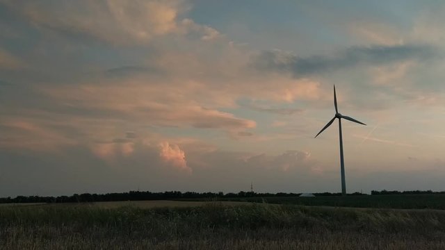 Wind turbines for green energy generation in fast motion time-lapse at dusk in Burgenland plains.
