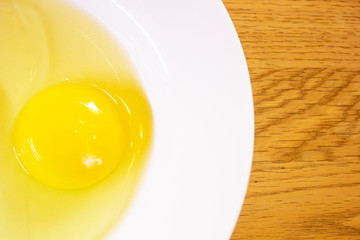 Close up One Yolk Egg On white Plate in Brown Wood Stripe Background