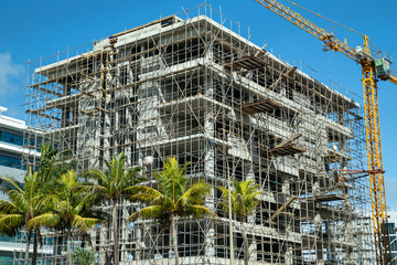 High building under construction with scaffolding and building crane in Port Louis and  on...