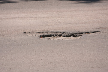 Bad roads. Hole in the asphalt, the risk of movement by car, bad asphalt, dangerous road, potholes in asphalt, pit unsafe hole road concept. Way markings in the pit.