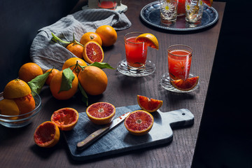 Freshly Squeezed Sicilian Blood Orange Juice with Vintage Juicer, Pitcher, and Sliced Oranges on Cutting Board