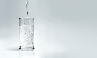 Naklejka na ściany i meble pour water into the glass on a white background