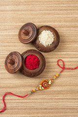 Indian festival: Raksha Bandhan background with an elegant Rakhi, Rice Grains and Kumkum. A traditional Indian wrist band which is a symbol of love between Brothers and Sisters.