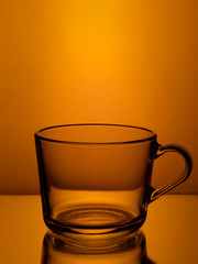 empty glass mug on orange background..